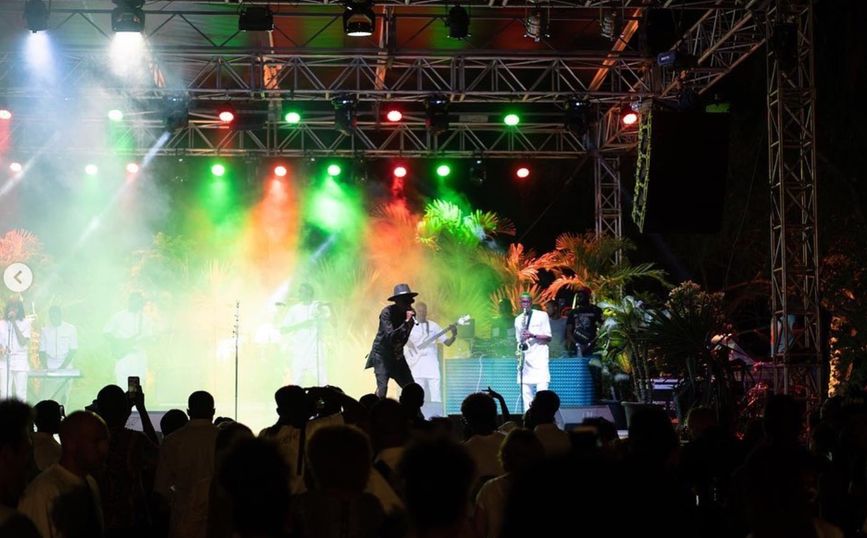 Live band performing on an outdoor stage lit in red and green