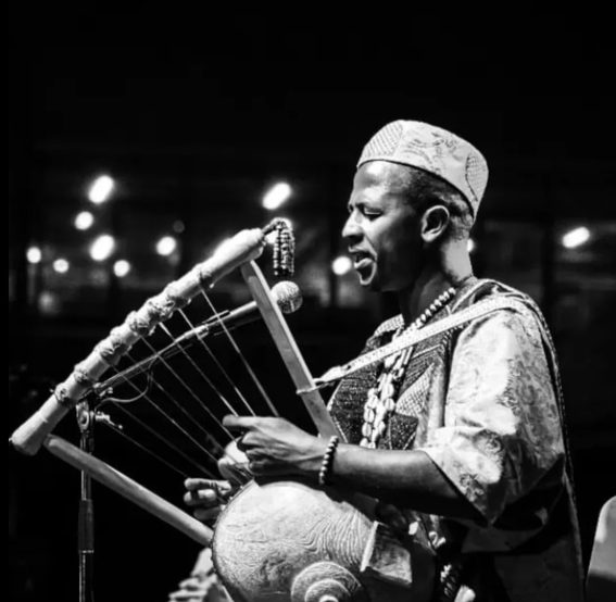 Black and white photo of a musician performing on a kora