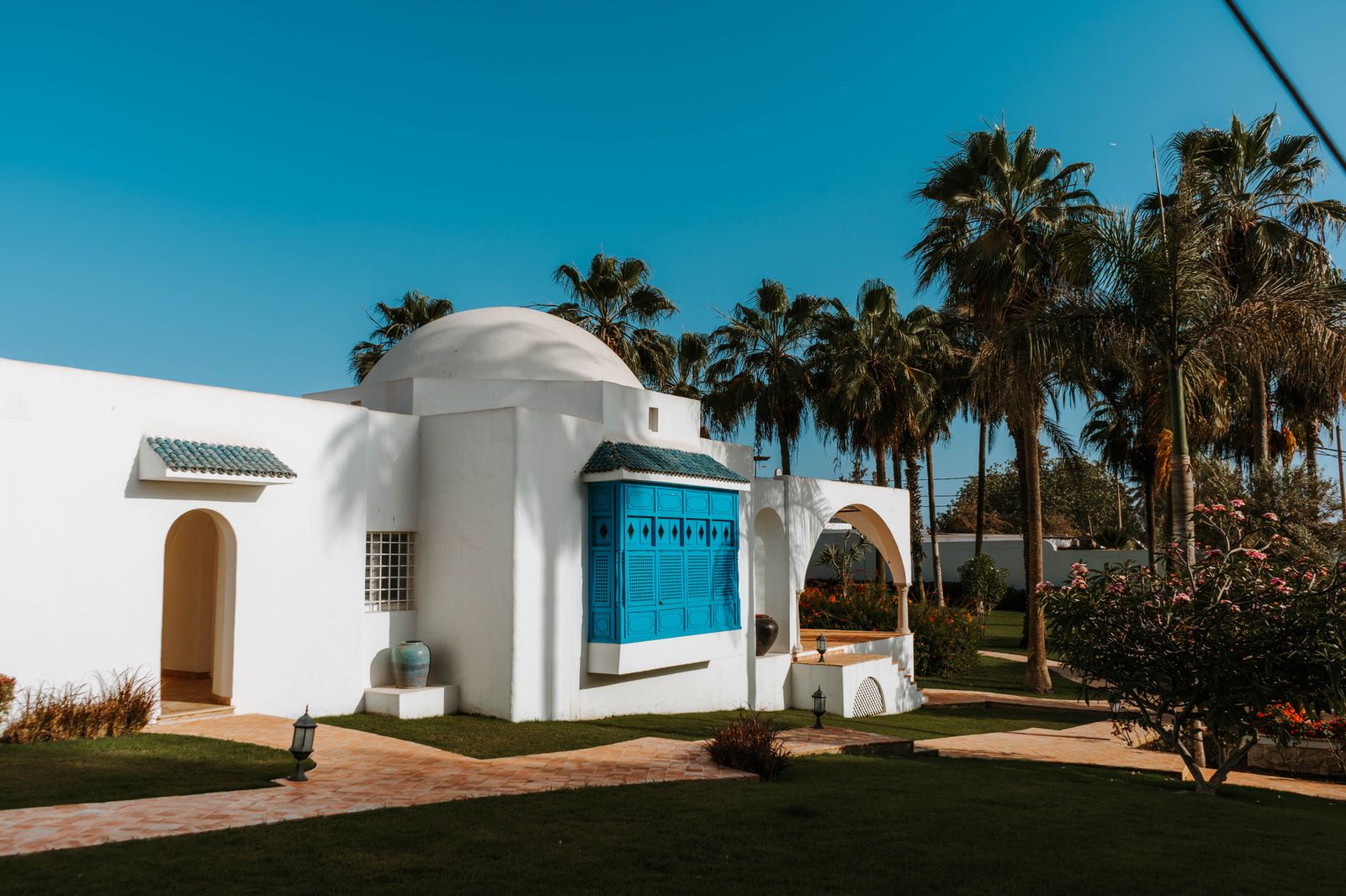 White villa with blue Tunisian-style shutters and door under a clear sky
