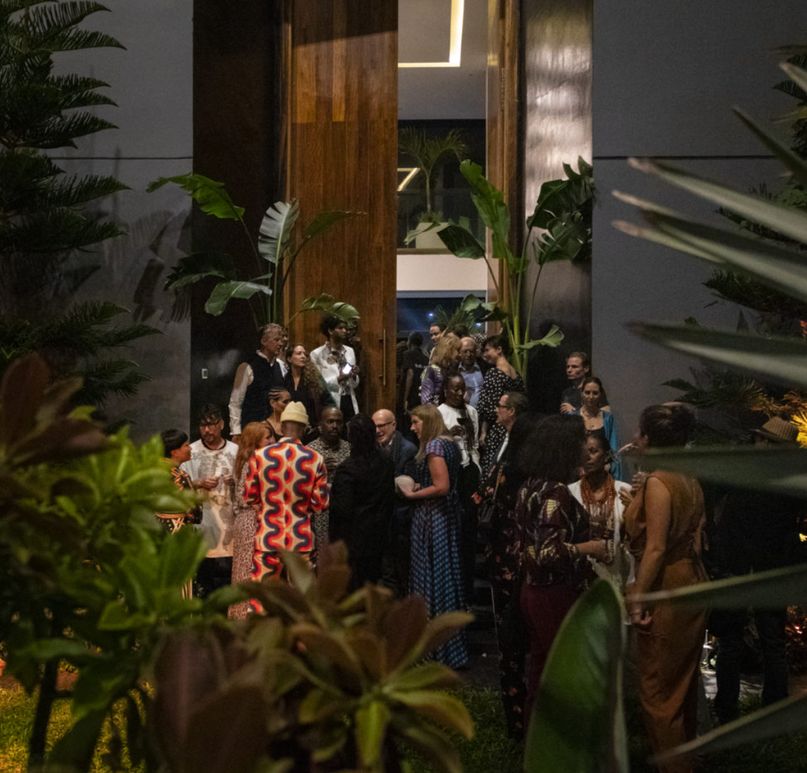 Guests gathering at the villa's wooden entrance doors at night, surrounded by tropical planting